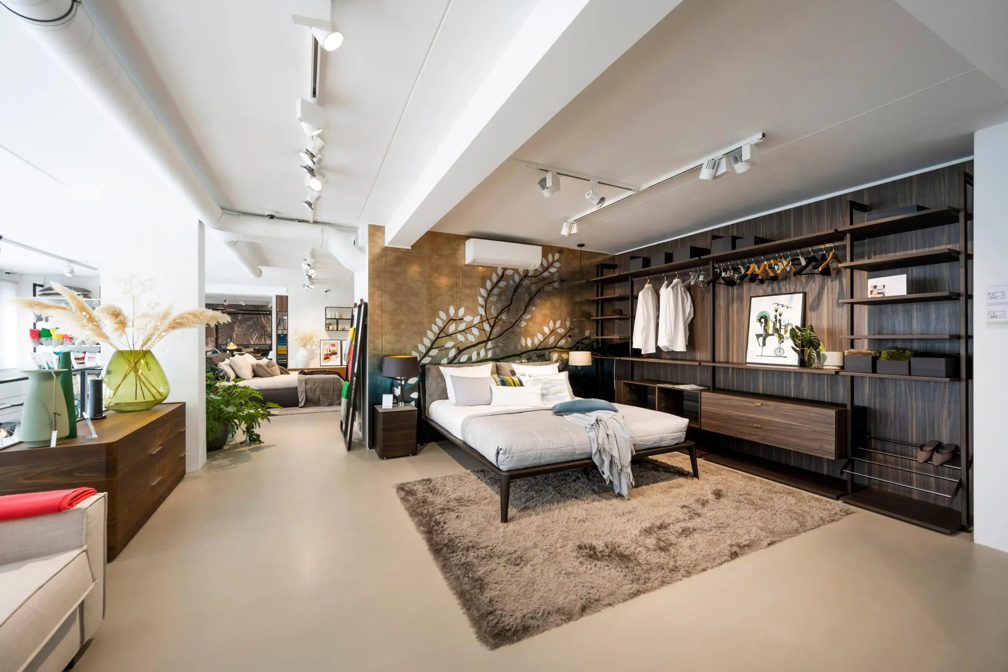 Modern ingerichte slaapkamer in een showroom aan de Oostelijke Handelskade met een open kledingkast, decoratief wandontwerp en strak interieur.